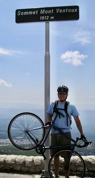 Dominic holding his single-gear bicycle aloft at the summit of Mont Ventoux!